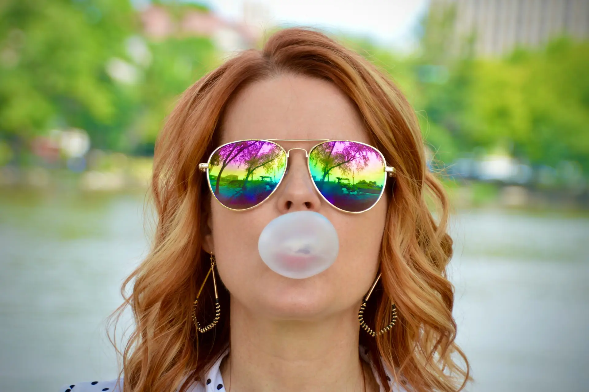 a woman wearing sunglasses blowing a bubble